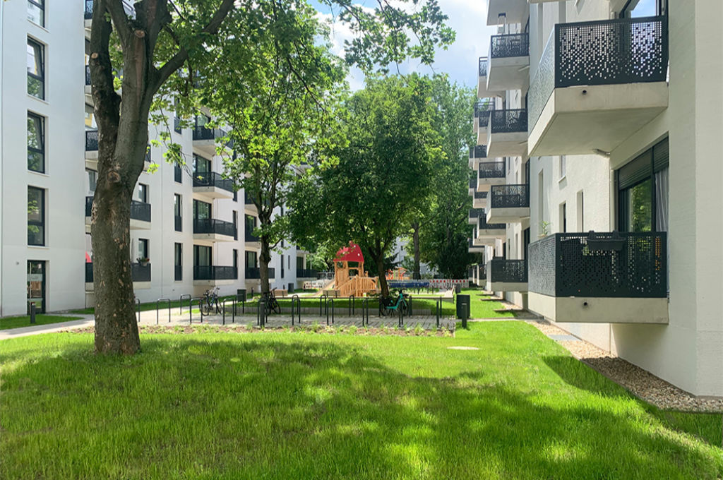 Innenhof in der Ifflandstraße mit viel Grünfläche, Bäumen und einem Spielplatz mit Sandkasten